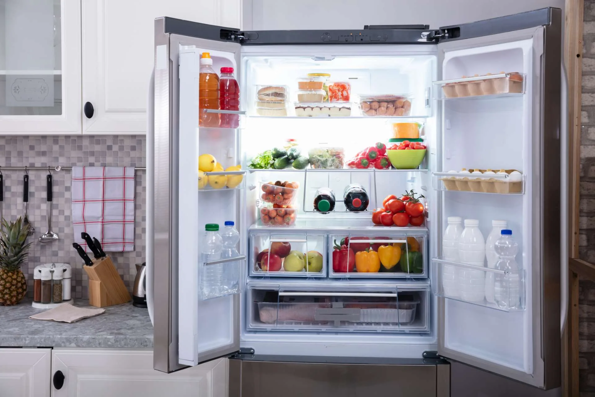 Refrigerator door is open showing fresh produce. The fridge is working properly and the light is on. The fridge repairman fixed the fridge in Edmonton