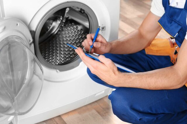 Professional Repair man inspecting washing machine and going through the maintenance checklist