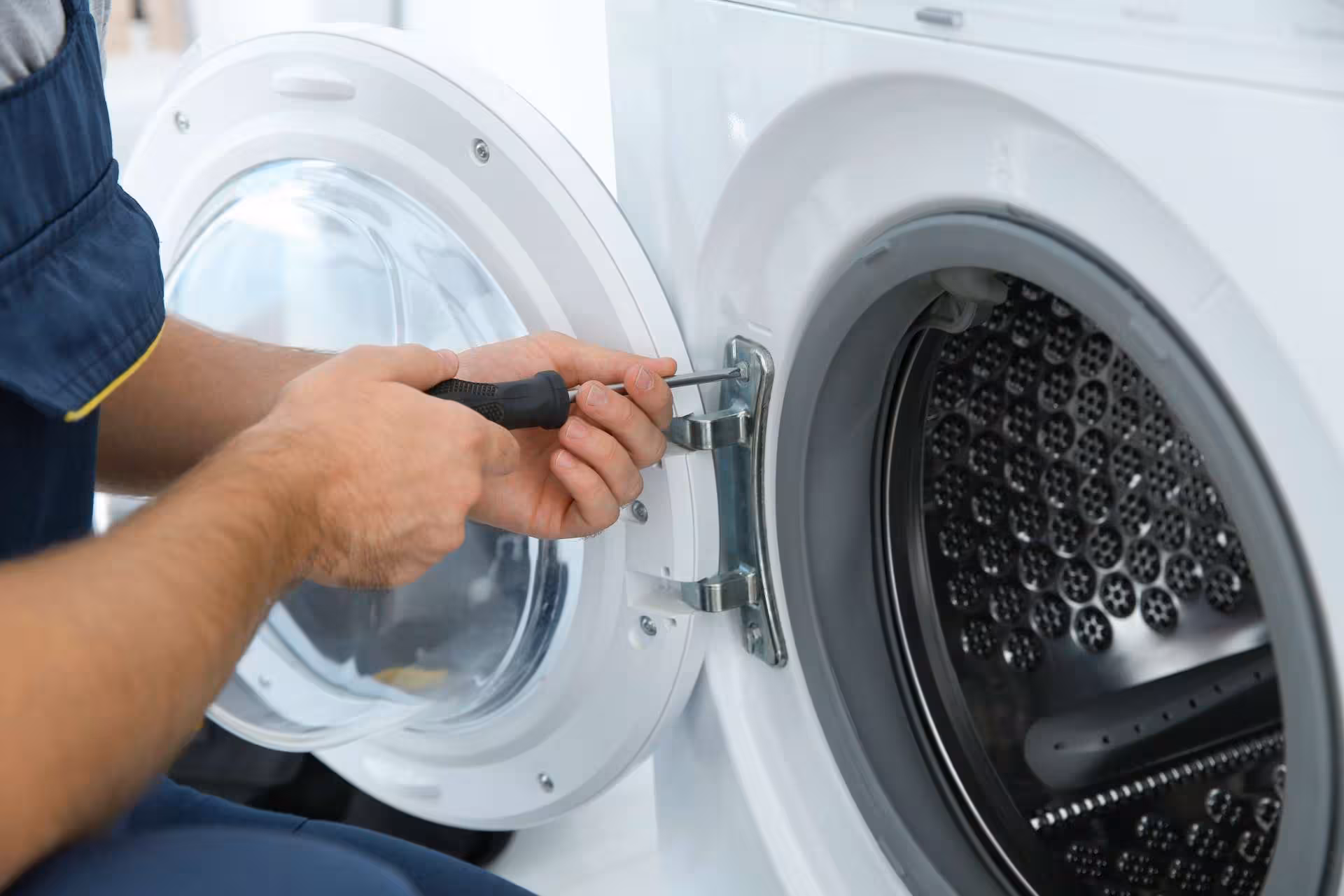 washing machine door is being removed so that the washing machine can be repaired.