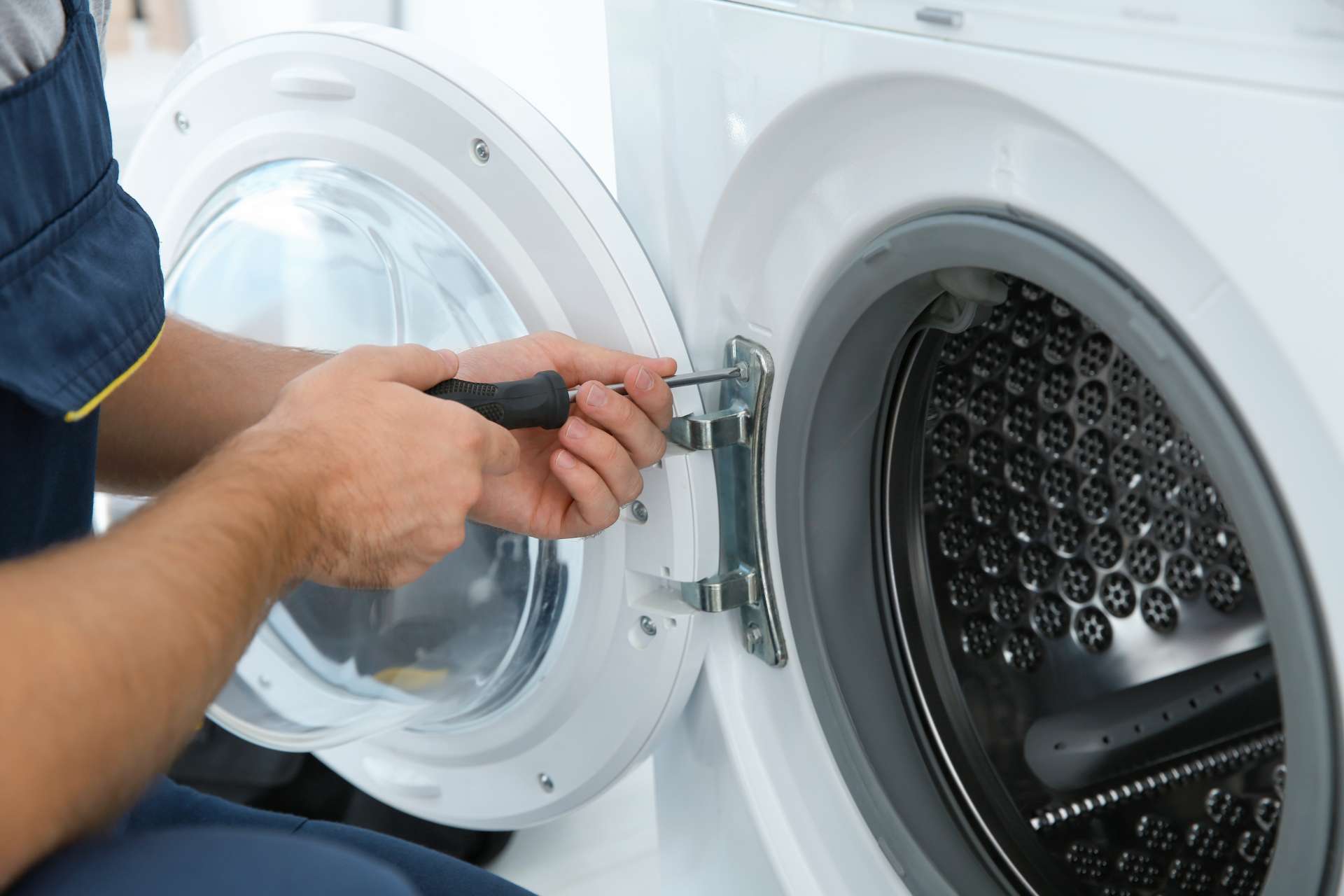 washing machine door is being removed so that the washing machine can be repaired.