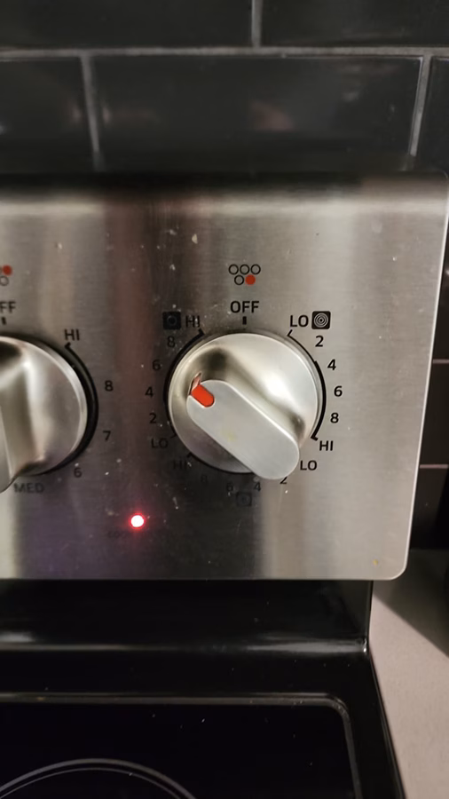 The Samsung stove Fast Boil burner glowing pink during a post-repair function test. The burner is responding correctly to the knob position after the infinite switch replacement.