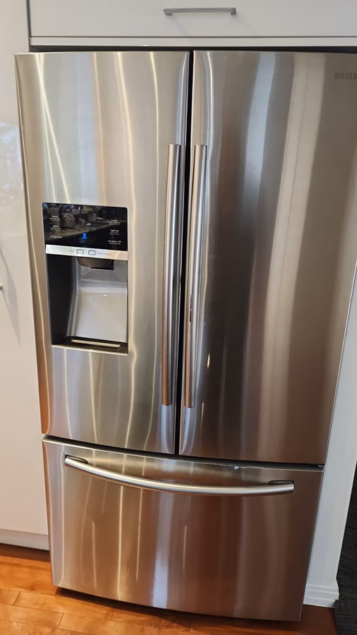 Samsung French door refrigerator with water and ice dispenser in a kitchen, stainless steel finish.